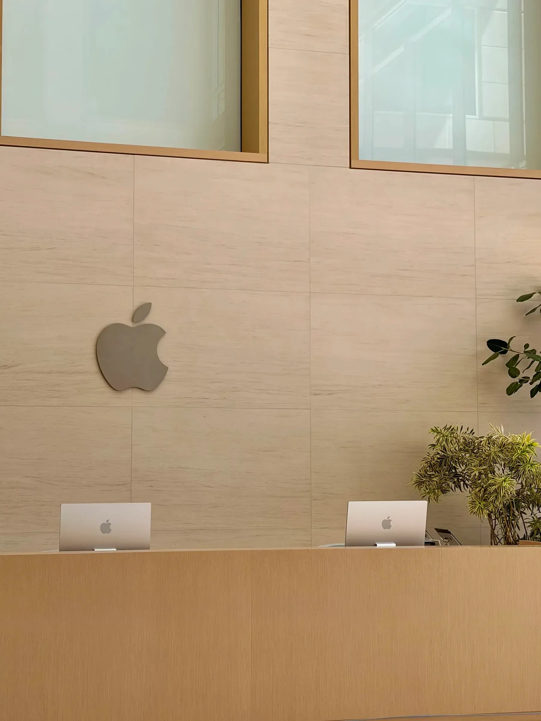 Apple logo and wooden reception desk with MacBooks at One Infinite Loop, Cupertino