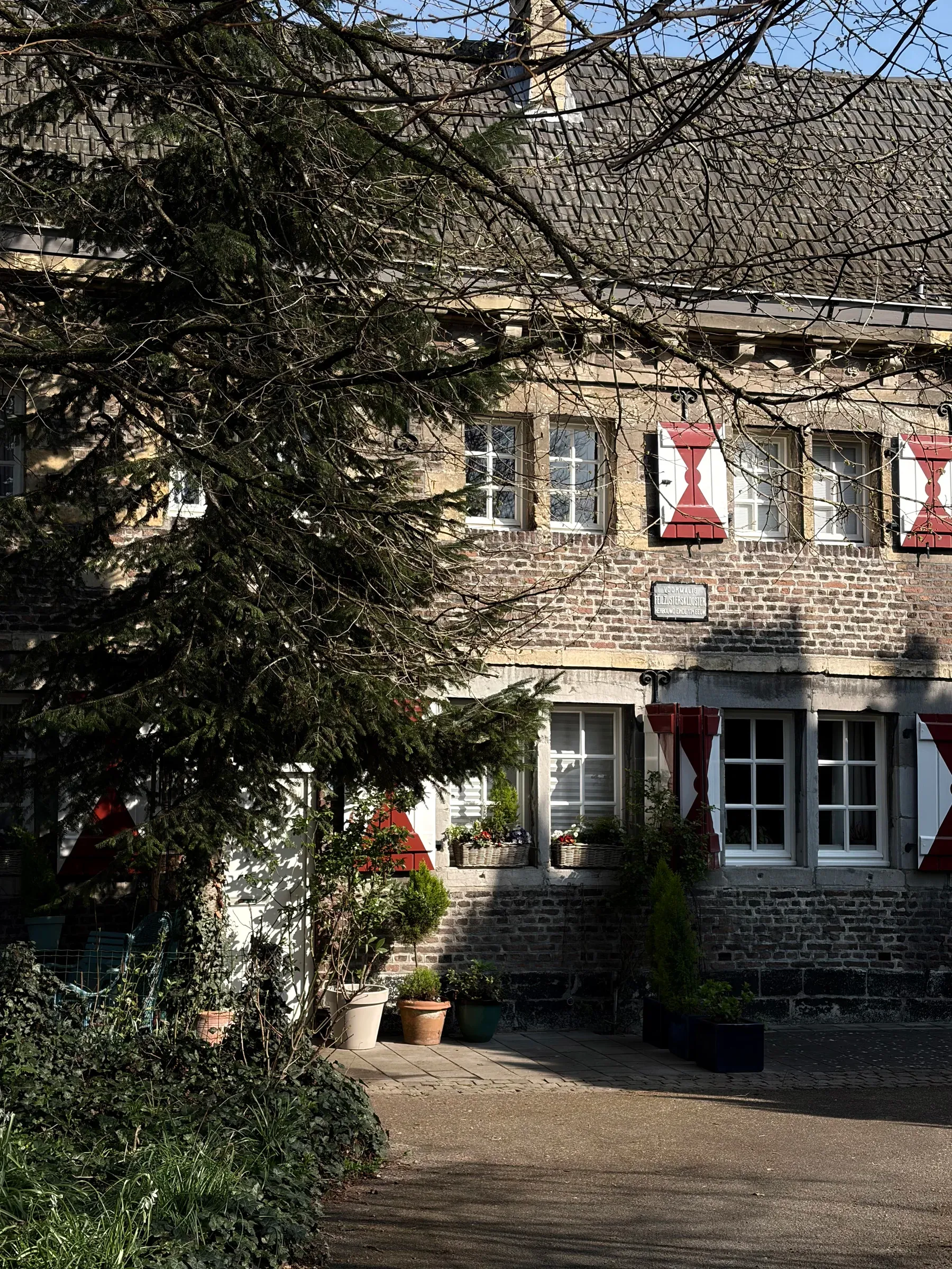Stone house with red-and-white Maastricht flags partly hidden by trees