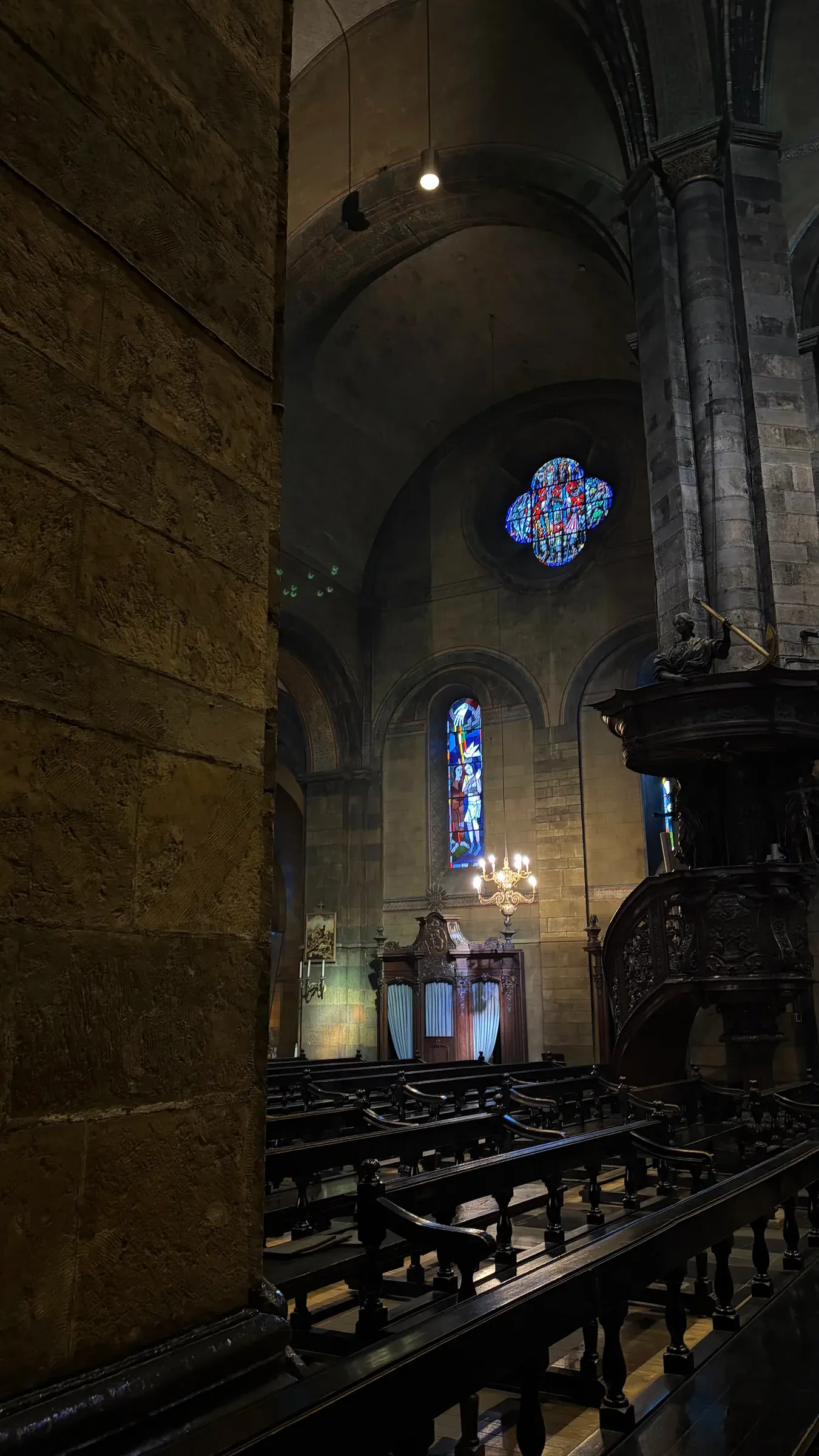 Dim side aisle, pulpit, and stained glass inside the Basilica of Our Lady