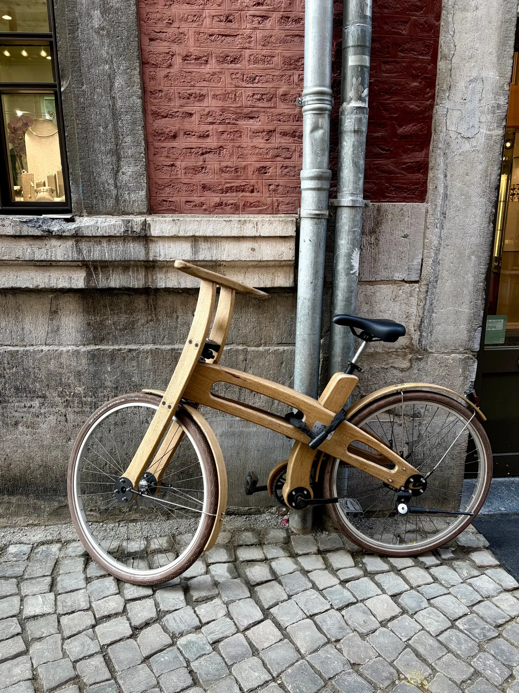 Wood-framed bicycle locked against a red stone facade in Maastricht