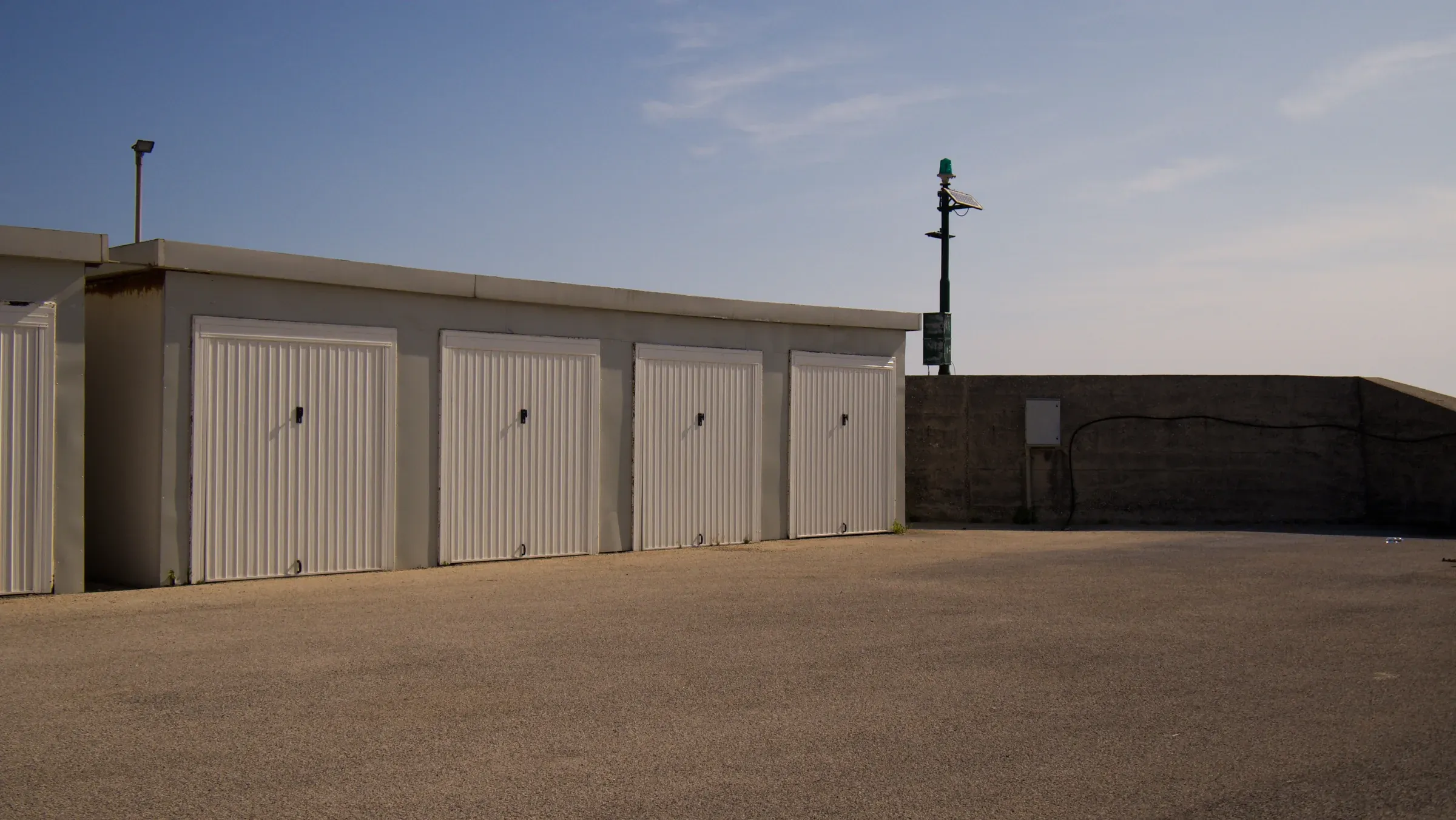 Row of white roll-up storage garages at a marina under a clear summer sky