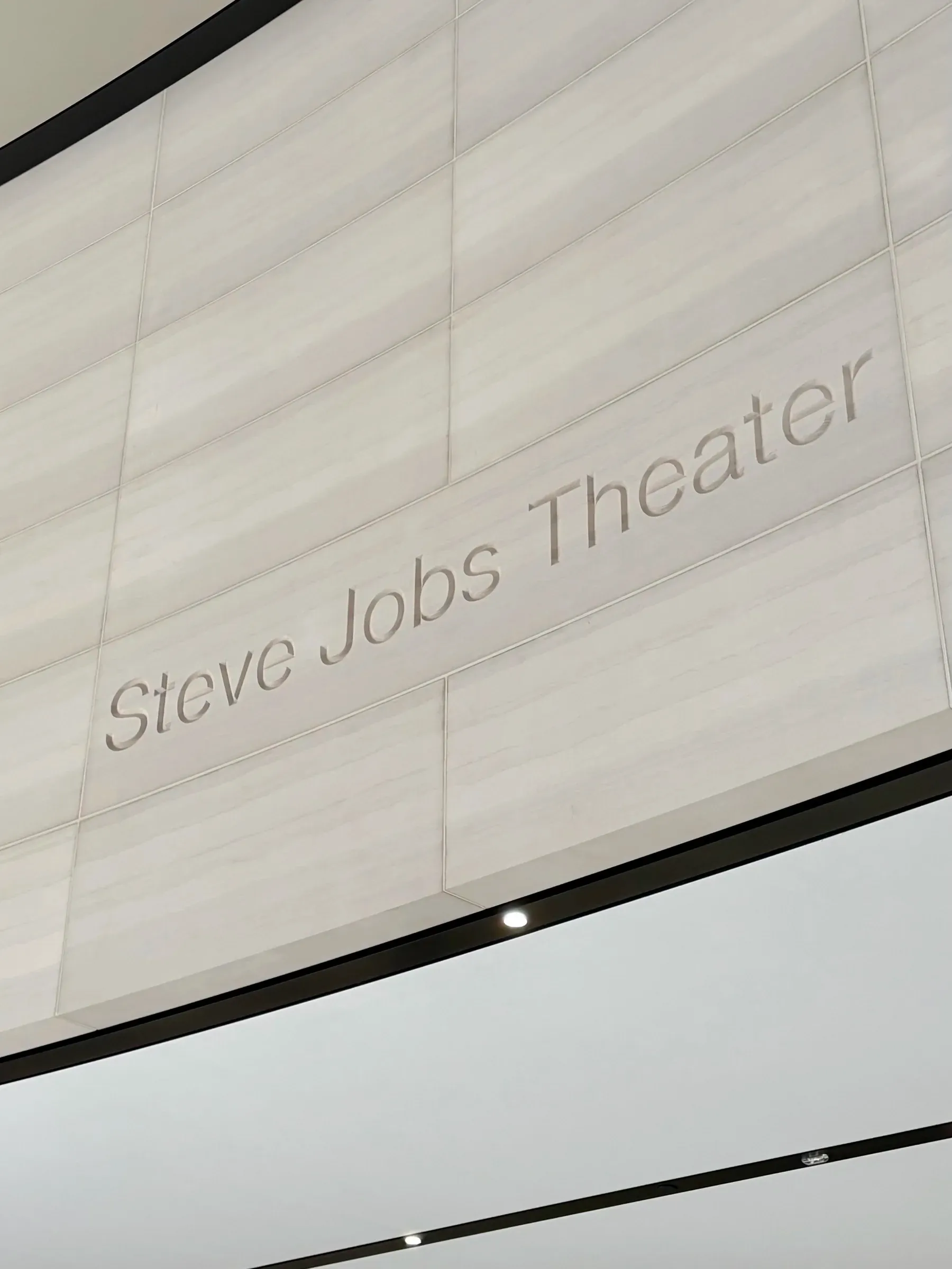 Steve Jobs Theater sign engraved on the curved stone wall at Apple Park