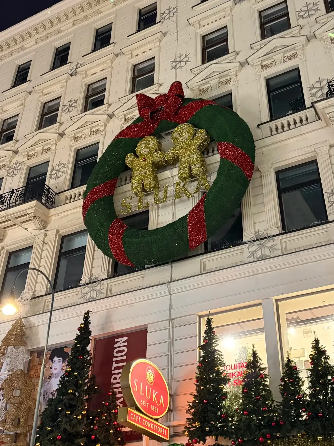 Large Christmas wreath and Café Sluka sign on a Vienna street facade