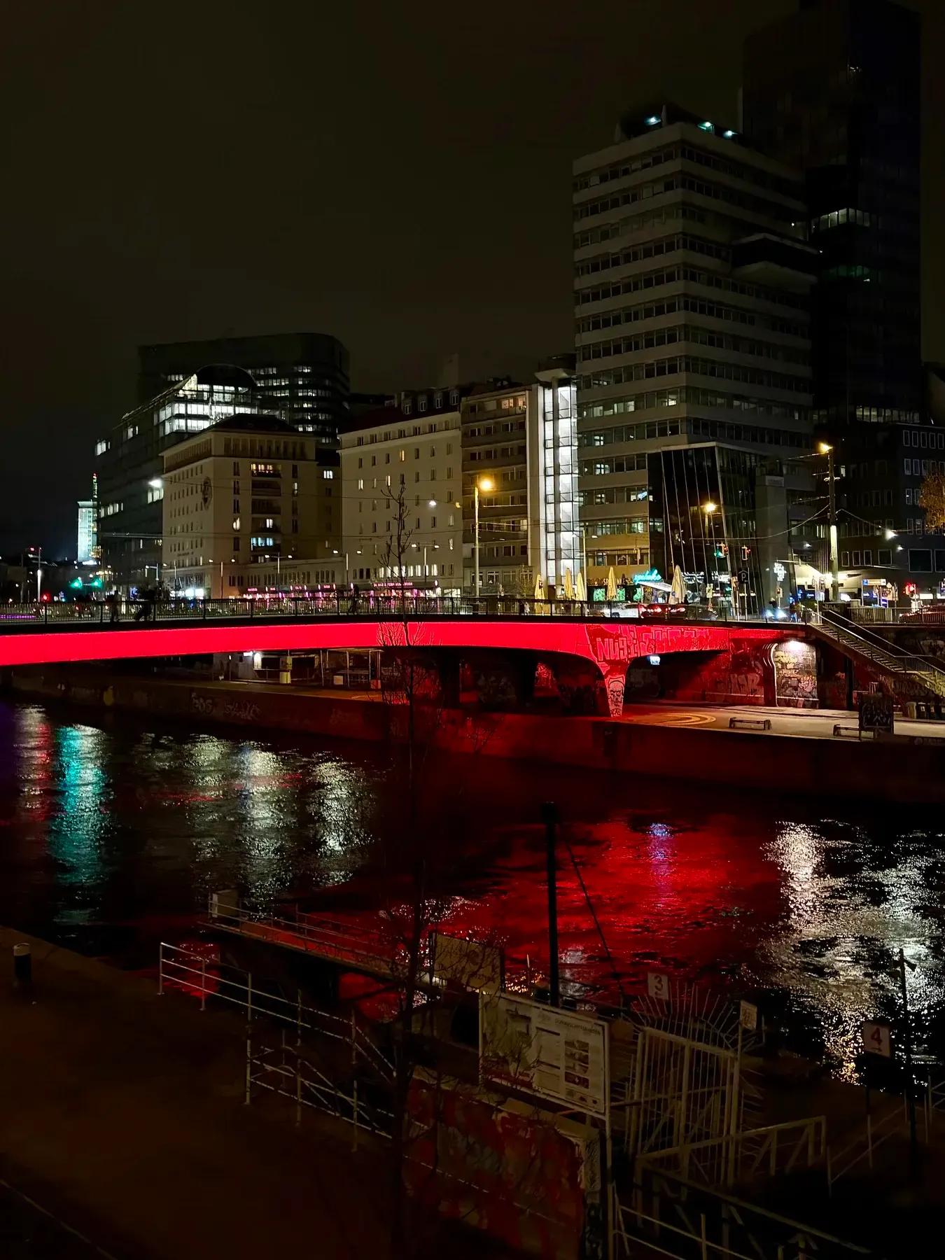 Red bridge lights reflected in the Donaukanal at night