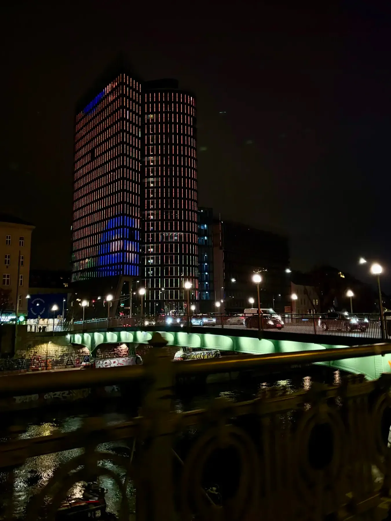 Lit office tower and bridge above the Donaukanal at night