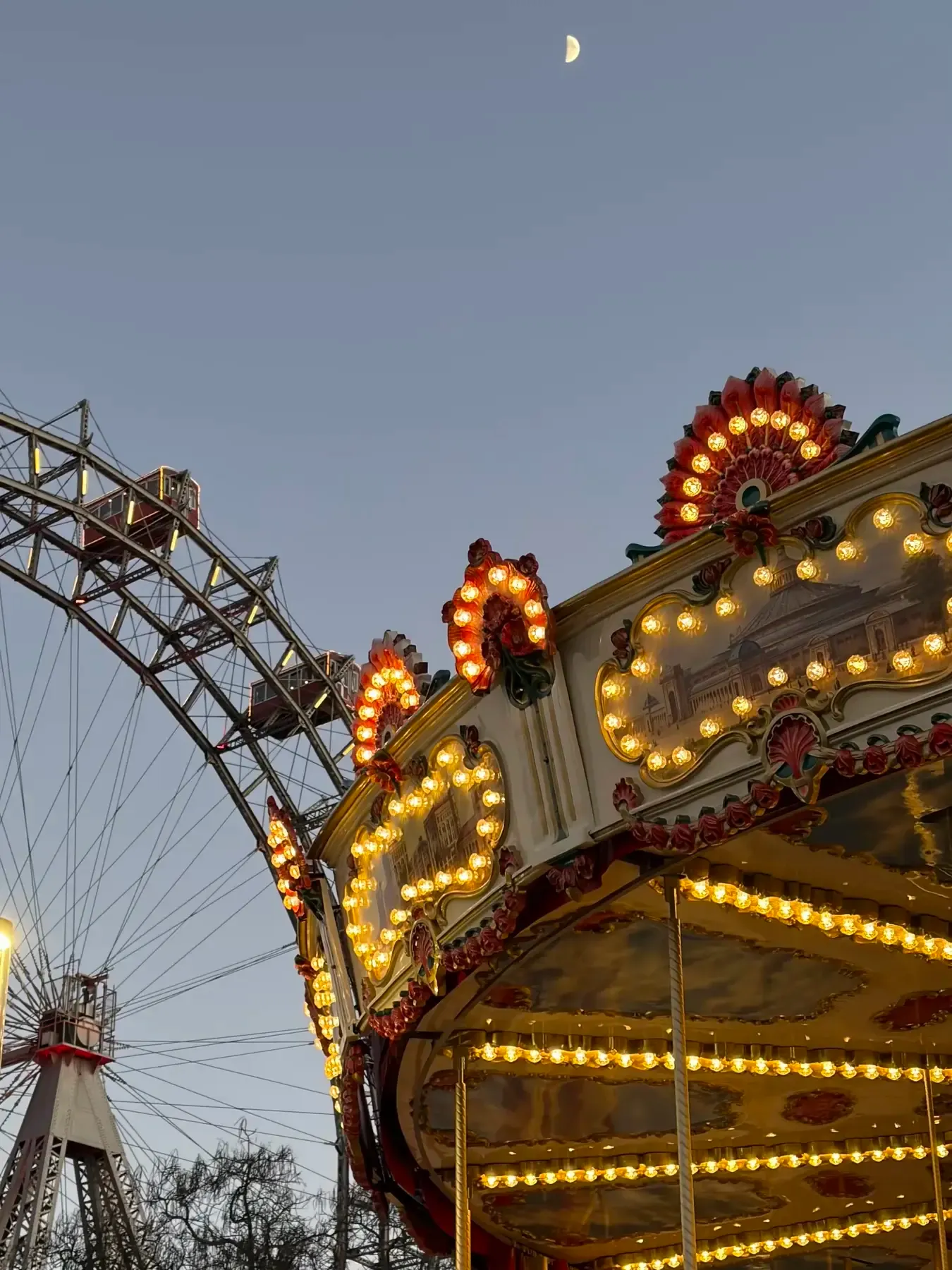 Carousel lights with the Giant Ferris Wheel and crescent moon behind