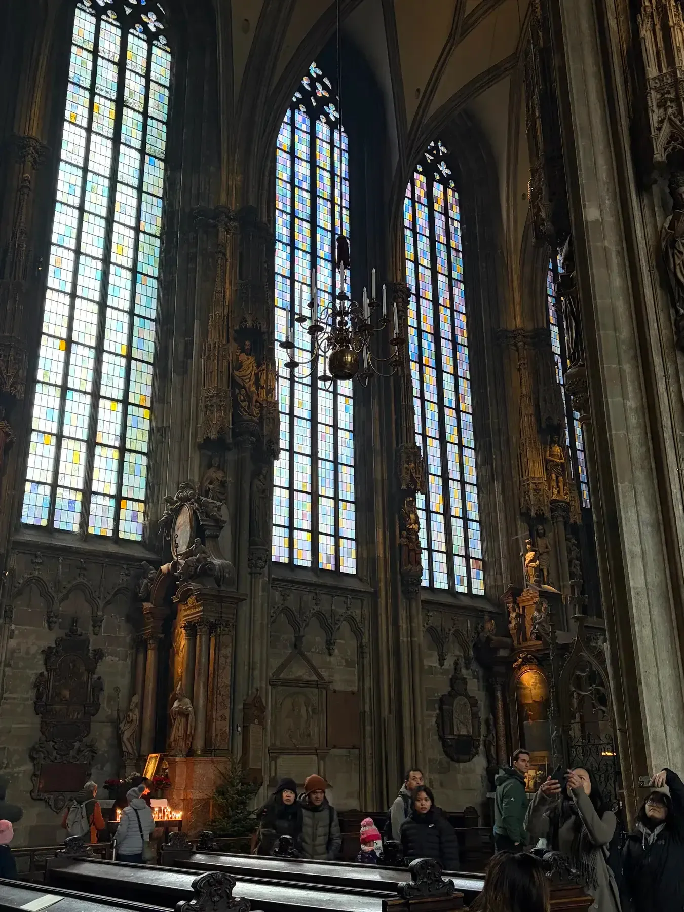Tall stained-glass windows and stone columns inside Stephansdom